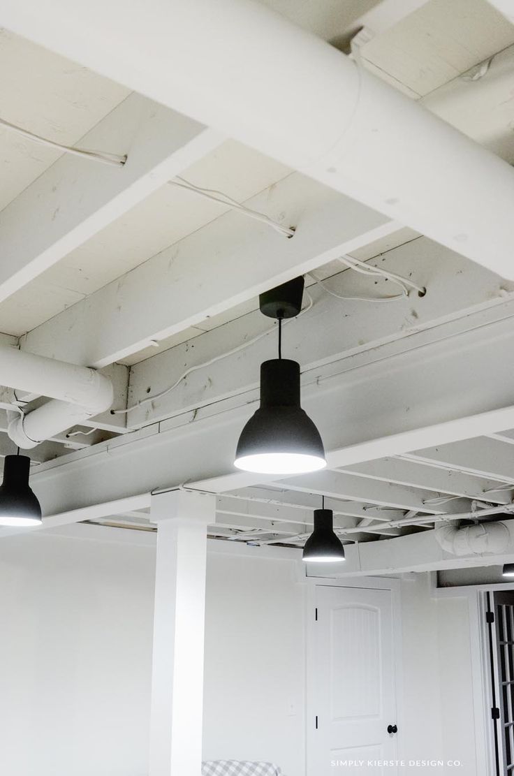 an empty room with three black lamps hanging from the ceiling