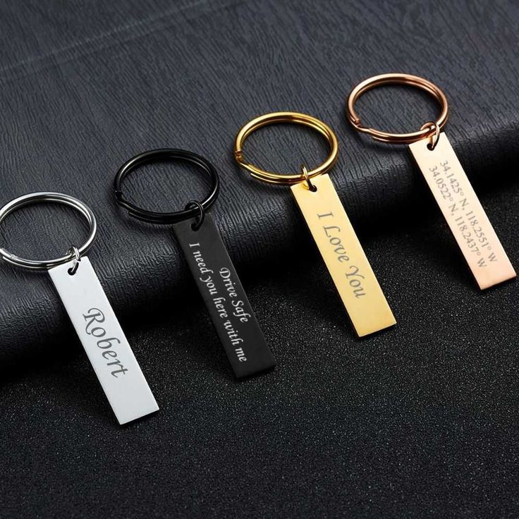 three different types of keychains with names on them sitting on a black cloth