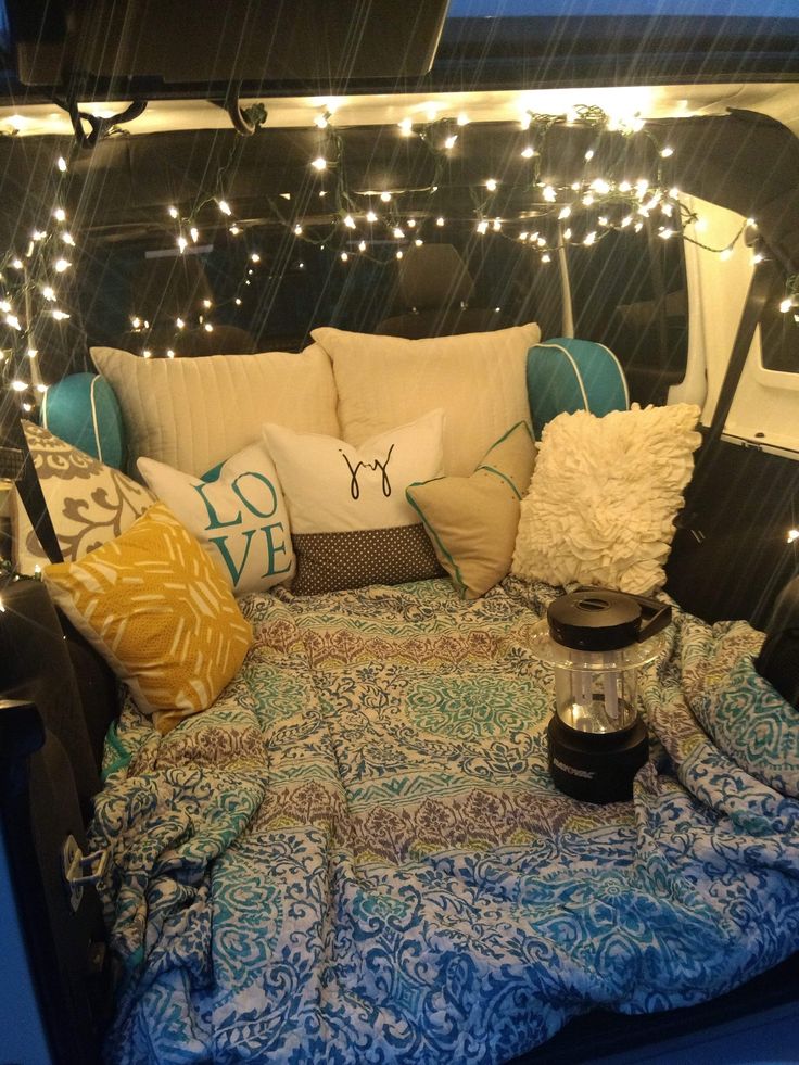 a bed with pillows and lights in the back of an rv parked on the side of the road