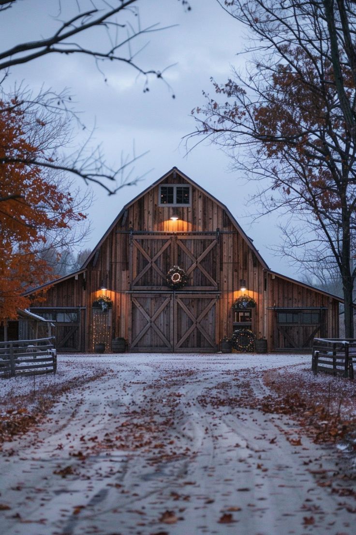 a barn in the middle of winter with snow on the ground and trees around it