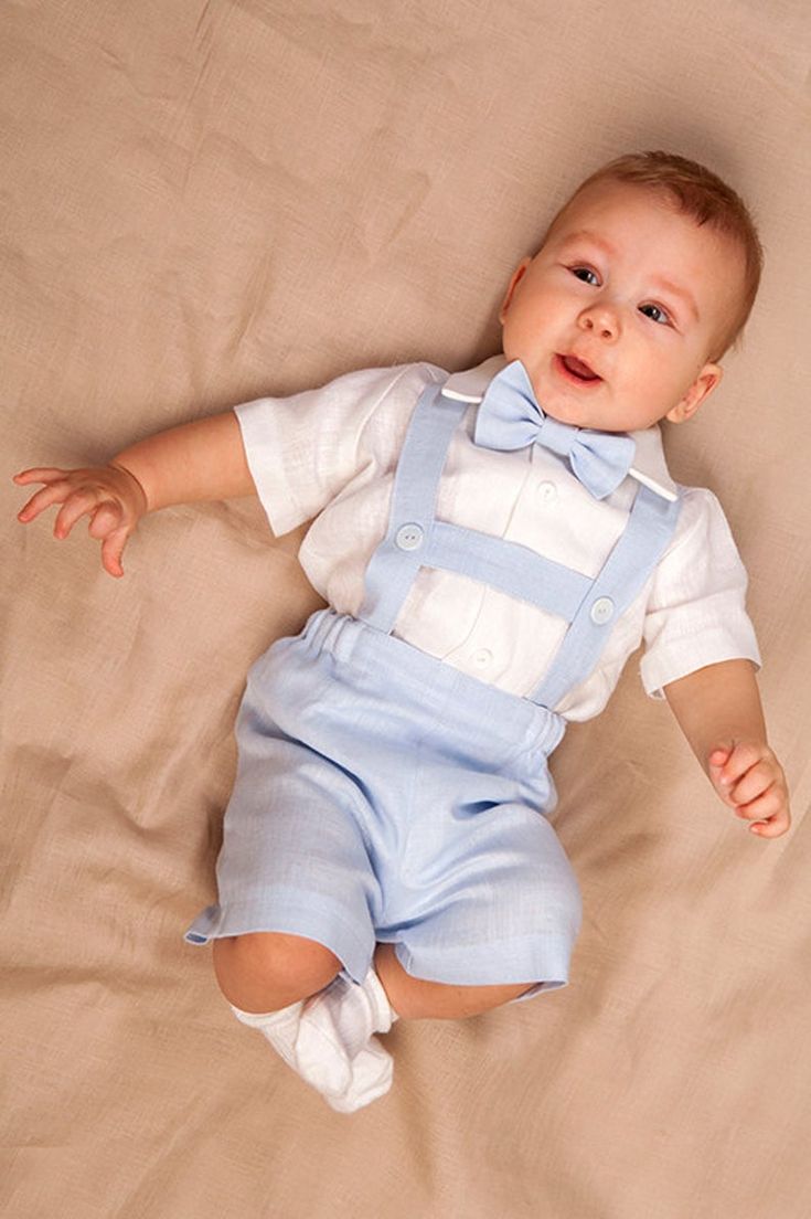 a baby laying on top of a bed wearing blue overalls