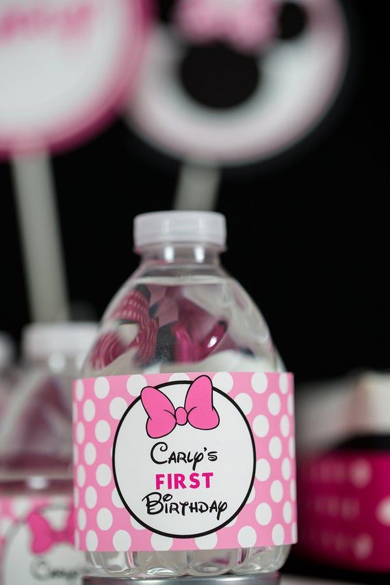 a pink and white minnie mouse first birthday water bottle label with candy in the shape of a bow