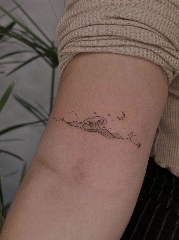 a woman's arm with a wave tattoo on the left side of her arm