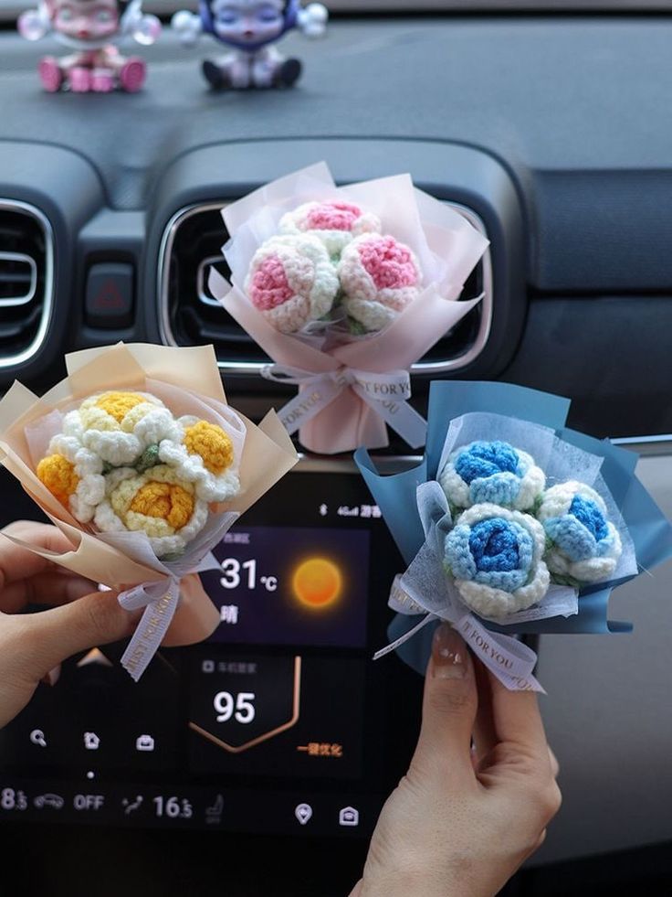 two hands holding flowers in front of a car dashboard