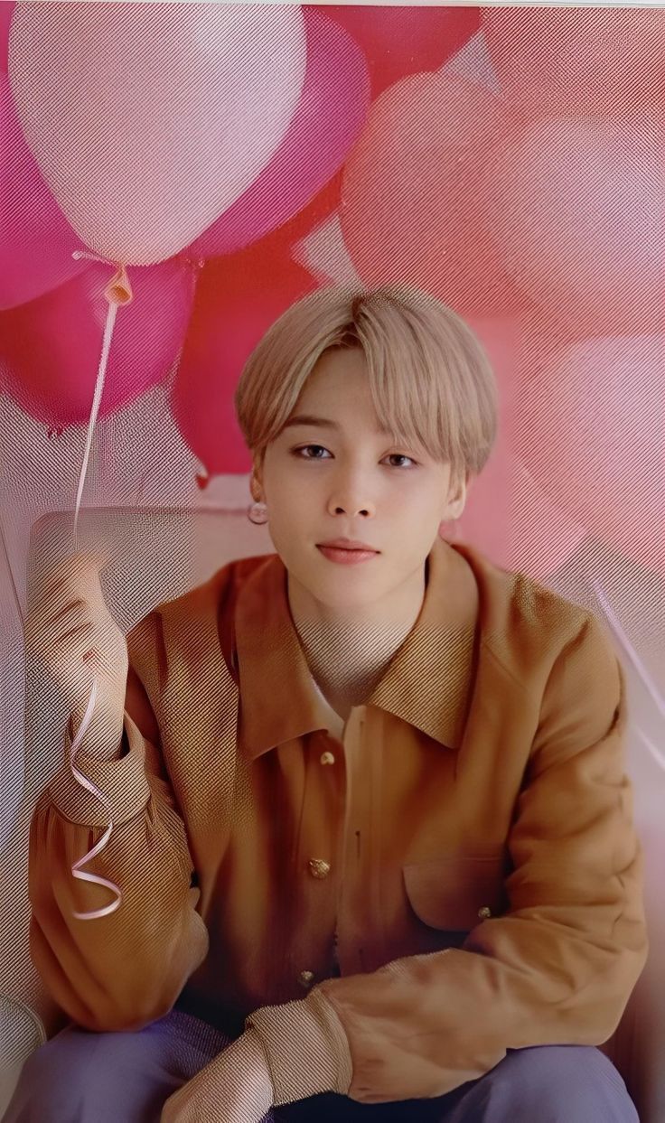 a young man sitting on top of a chair holding a balloon