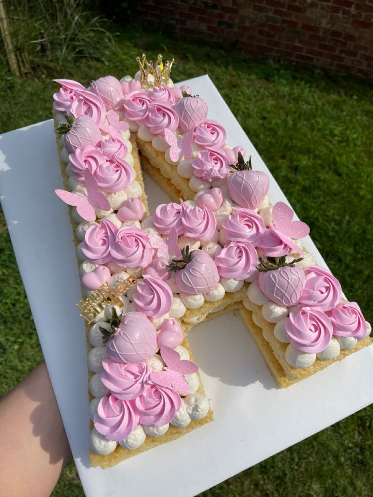 a cake shaped like the letter k with pink frosting roses on it, sitting on top of a table