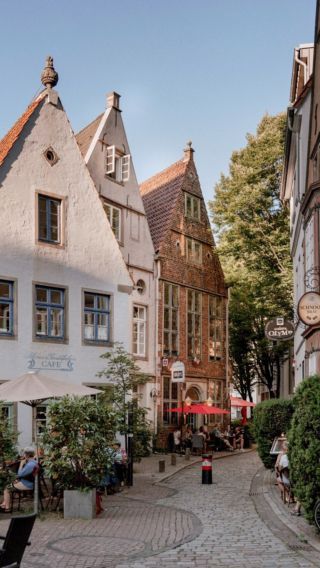 people are sitting at tables on the cobblestone street in an old european town