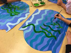 children are painting on paper with green and blue colors