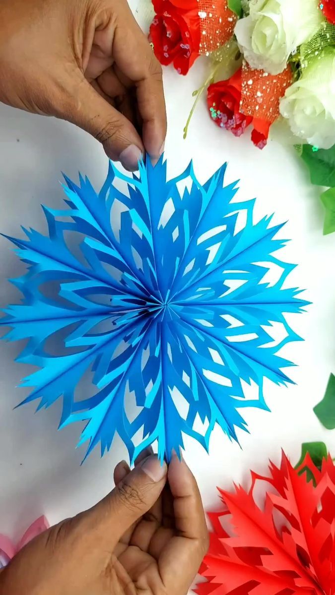 two hands holding blue and red paper flowers