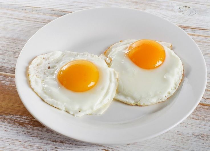 two fried eggs are on a white plate