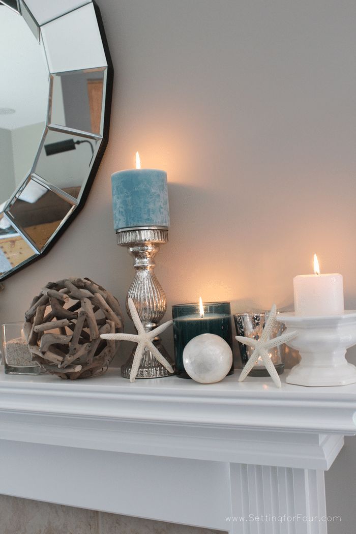 a mantle with candles, seashells and other items sitting on top of it