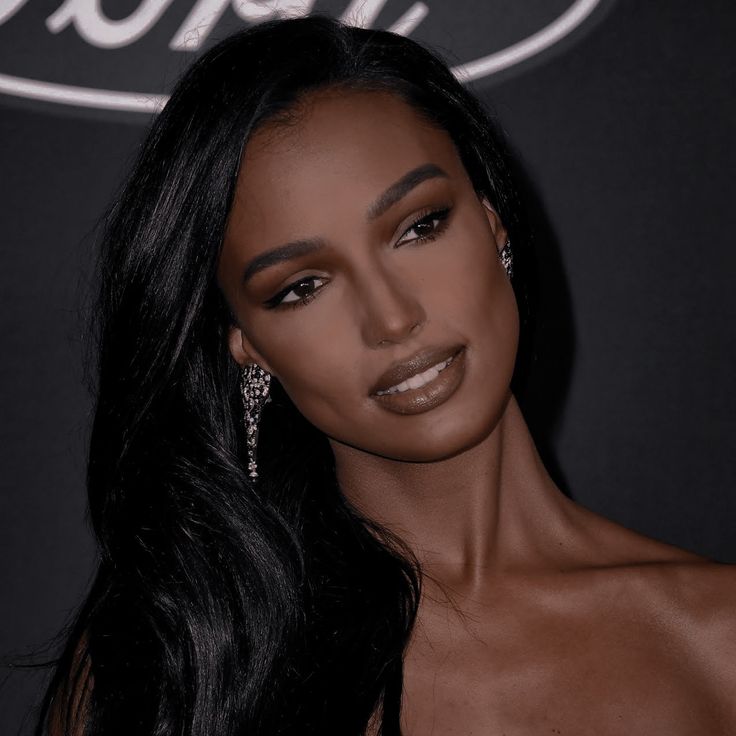 a woman with long black hair wearing earrings