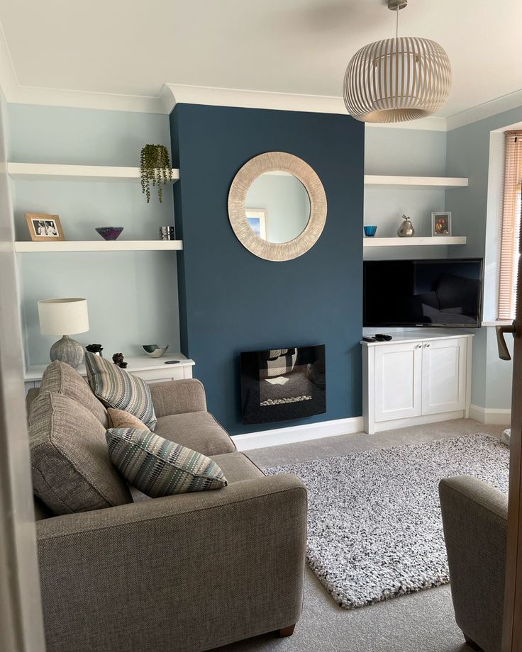 a living room filled with furniture and a fire place under a round mirror on the wall