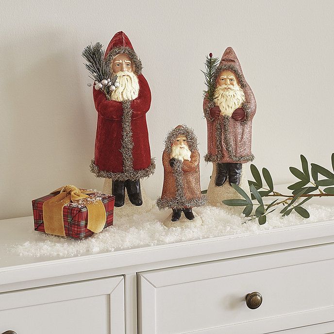 three gnome figurines sitting on top of a white dresser