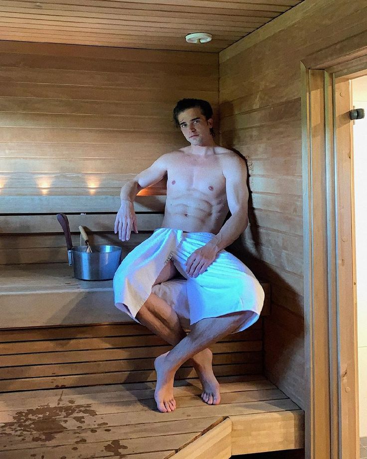 a man sitting in a sauna with no shirt on and his legs crossed out