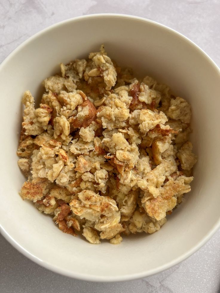 a white bowl filled with oatmeal and nuts on top of a table