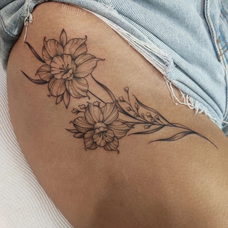 a woman's stomach with flowers and leaves tattooed on the back of her thigh