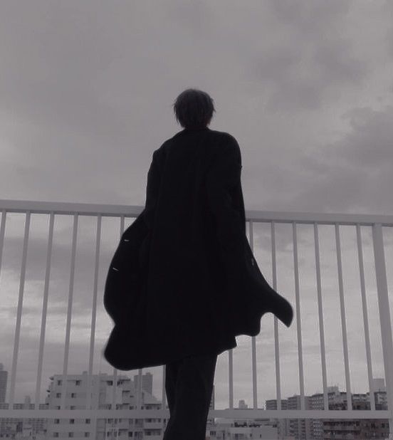 a man standing on top of a balcony next to a tall building with buildings in the background