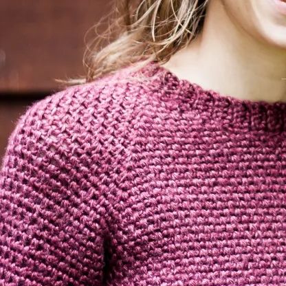 a close up of a woman wearing a pink sweater