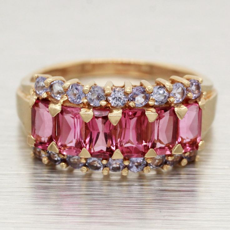 Size: 8.00 Pink Tourmaline:   -  Color: Pink   -  Carat Weight Total: 1.50ctw approx.   -  Cut Shape: Emerald   -  Stone Count: 6 Tanzanite:     -  Color: Light Purple   -  Carat Weight Total: 0.50ctw approx.   -  Cut Shape: Round   -  Stone Count: 18 Ring Height: 9.47 - 2.05 mm Shank Thickness: 1.07 mm Ring Profile: 5.74 mm Total Weight: 3.9 grams Hallmark: STS 14K Composition: This item has been tested and is guaranteed to be solid 14K yellow gold. Era: Vintage Condition: This item is in excel Formal Multi-stone Pink Ruby Ring, Formal Pink Multi-stone Sapphire Ring, Pink Tourmaline Birthstone Ring, Formal Pink Multi-stone Ruby Ring, Elegant Pink Tourmaline Birthstone Ring, Pink Round Tourmaline Jewelry, Luxury Pink Tourmaline Jewelry, Fine Jewelry Tourmaline In Pink, Emerald Stone