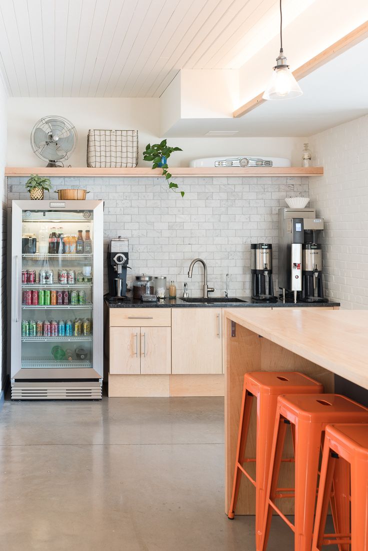 a kitchen with orange stools in front of an open refrigerator and coffee maker on the counter