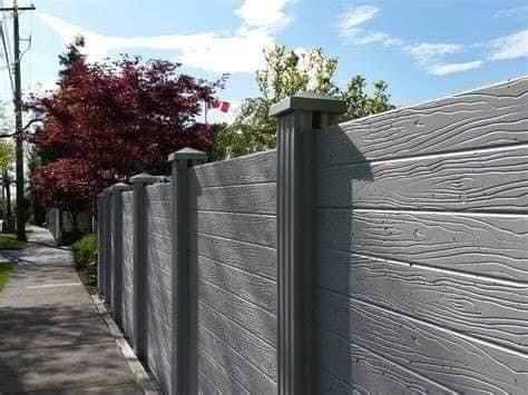 a long gray fence next to a sidewalk