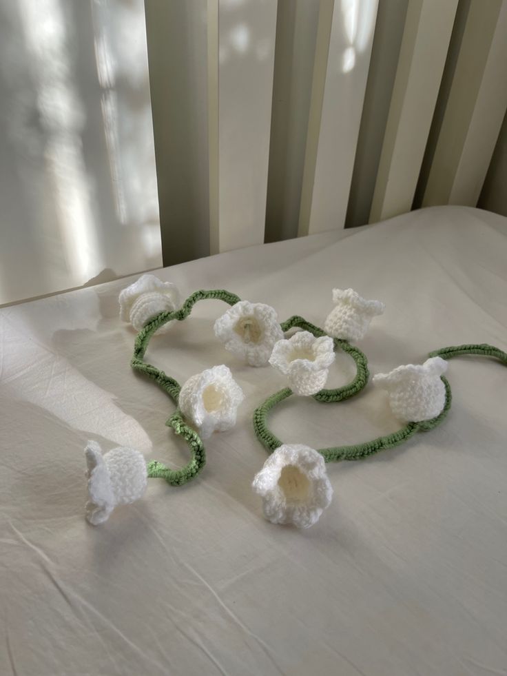 crocheted flowers are laid out on a white bed with green trimmings