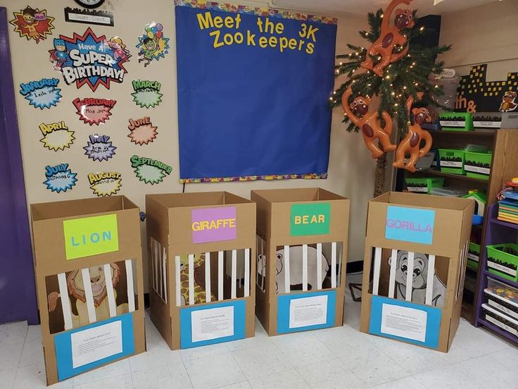 three cardboard boxes with pictures on them in front of a bulletin board and christmas tree