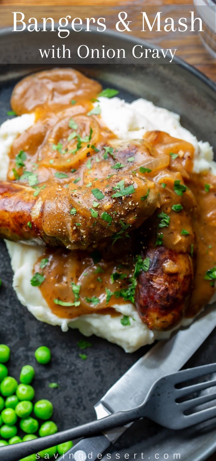 a plate topped with mashed potatoes and meat covered in gravy next to peas