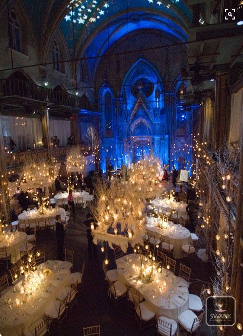 a room filled with lots of tables covered in white tablecloths and centerpieces