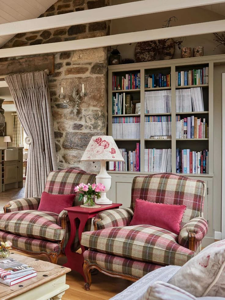 a living room filled with furniture next to a stone wall covered in bookshelves