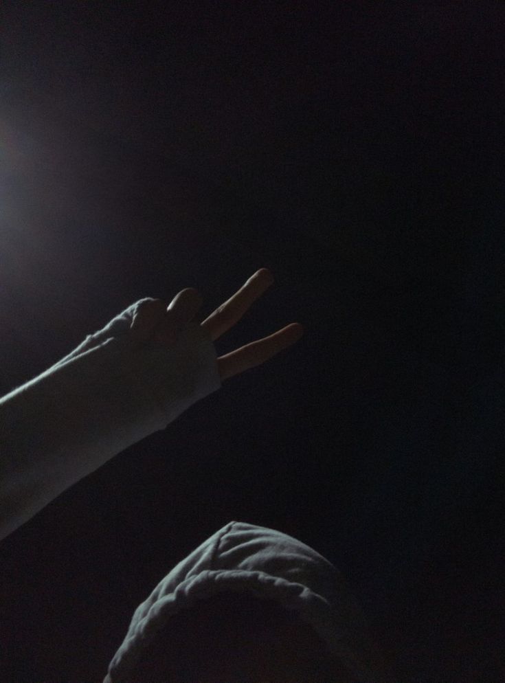 a person holding their hand up in the air with light shining on them from behind