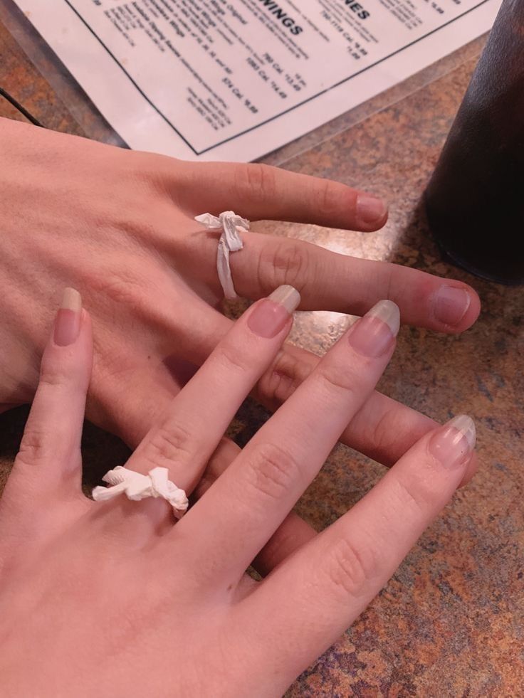 two people with wedding rings on their fingers at a table next to a drink and menu