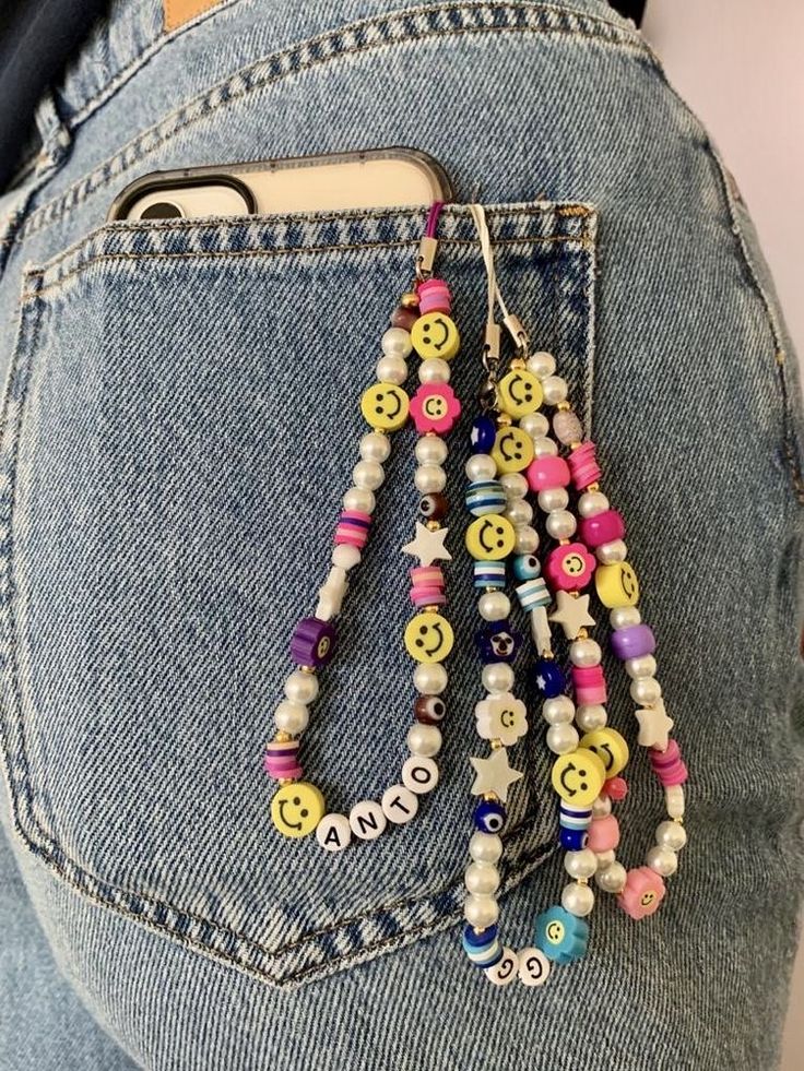 a woman's jeans pocket is decorated with colorful beads and smiley face buttons as she holds her cell phone