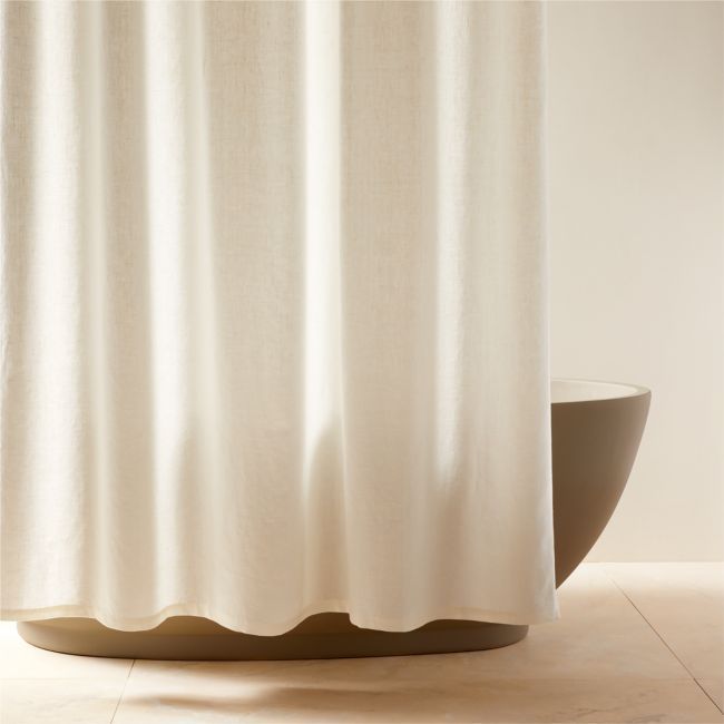 a white shower curtain sitting next to a round bowl on top of a tiled floor