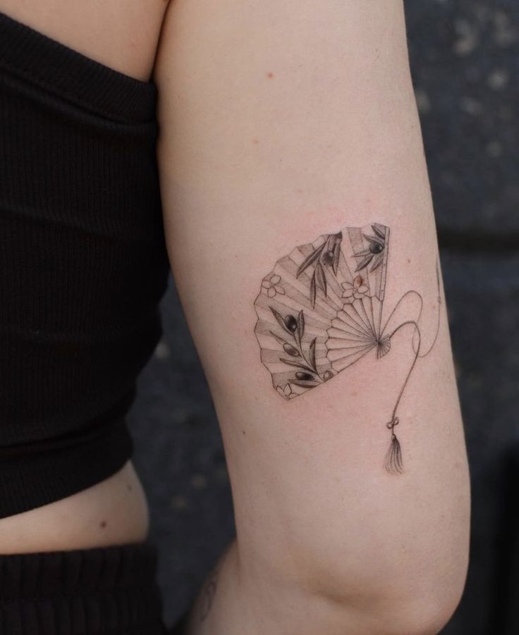 a woman's arm with a fan tattoo on the left side of her arm