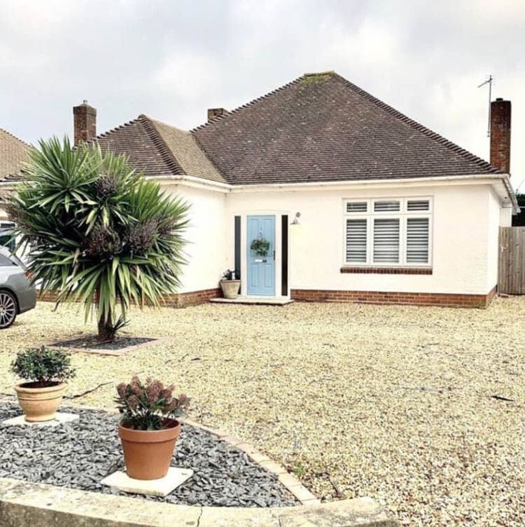 a car parked in front of a house next to a tree and potted plants