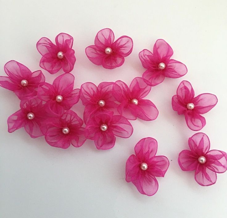 pink flowers and pearls are arranged on a white surface