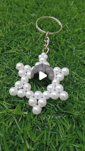 a keychain made out of pearls and beads on the grass with an arrow in the middle