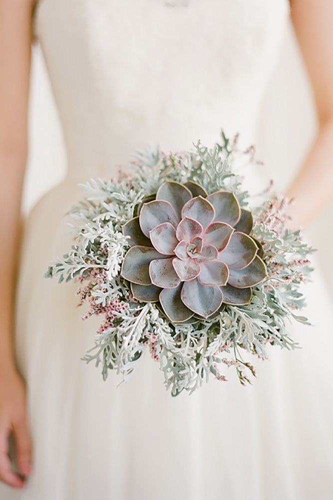 a bride holding a succulent bouquet in her hand