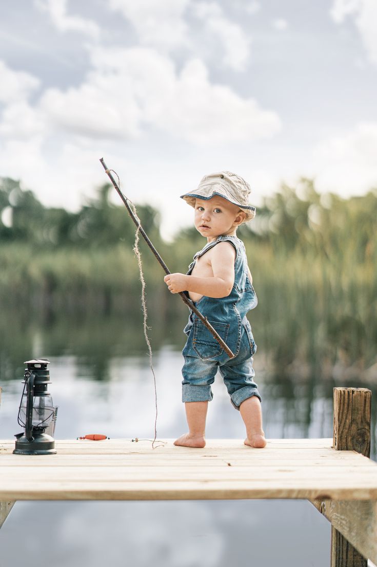 a little boy standing on a dock holding a fishing pole