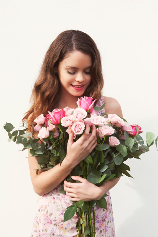 a woman holding a bouquet of pink roses