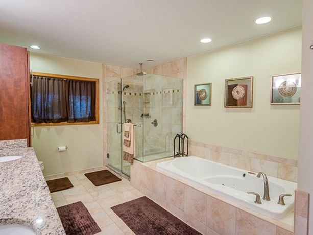 a large bathroom with marble counter tops and tile flooring, along with a walk in shower