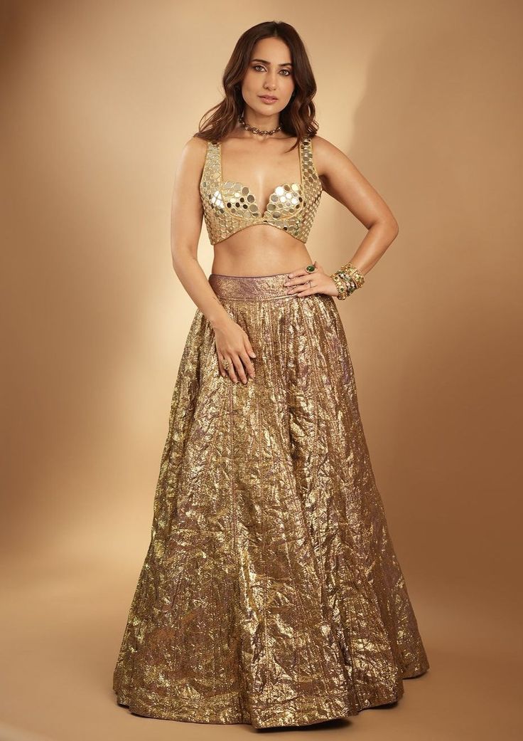 Introducing the Lampi lehenga set, a stunning ensemble that embodies timeless elegance and contemporary charm. The lehenga features intricate mirror work, meticulously handcrafted to accentuate its rich texture and vibrant hues. Paired with a matching mirror-embellished blouse and complemented by a mirror dupatta, this ensemble exudes grace and sophistication, perfect for any special occasion or celebration. Festive Gold Pre-draped Saree With Mirror Work, Glamorous Designer Pre-draped Saree For Navratri, Gold Lehenga Saree With Mirror Work, Gold Lehenga With Mirror Work For Reception, Gold Anarkali Set With Mirror Work For Navratri, Gold Sequined Dupatta For Designer Wear, Designer Art Silk Lehenga With Sequins, Gold Anarkali Set With Mirror Work For Diwali, Designer Gold Sequined Dupatta