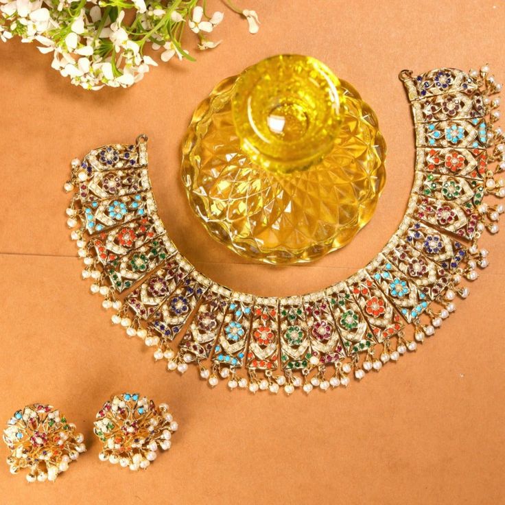 Featured is a traditional bridal Navratan necklace with a matching pair of round studs. The metal is gold plated sterling silver and the stones comprise precious freshwater pearls and a mix of real and synthetic navratan colored stones. The approximate Weight of the necklace is 60 GMs and the weight of the earrings is 15 gms. Festive Multi-stone Gold Jewelry Sets, Festive Gold Multi-stone Jewelry Sets, Multicolor Fusion Gold-plated Jewelry, Elegant Gold Multi-stone Kundan Necklace, Festive Gold Temple Necklace With Multi-stone, Multicolor Gold Plated Fusion Jewelry, Elegant Multicolor Jewelry Sets For Diwali, Festive Multi-stone Gold Necklace, Multicolor Fusion Gold Plated Jewelry