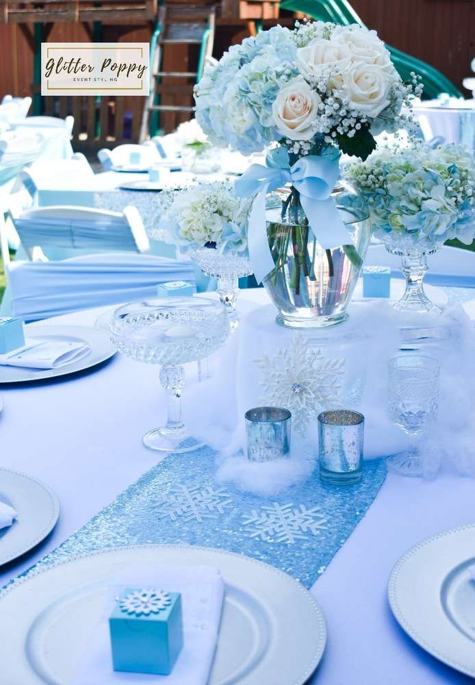 the table is set with white and blue flowers in vases, plates, napkins, and silverware