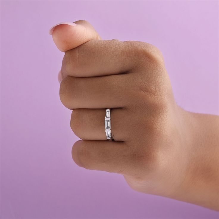 a woman's hand with a wedding ring on her finger, in front of a purple background