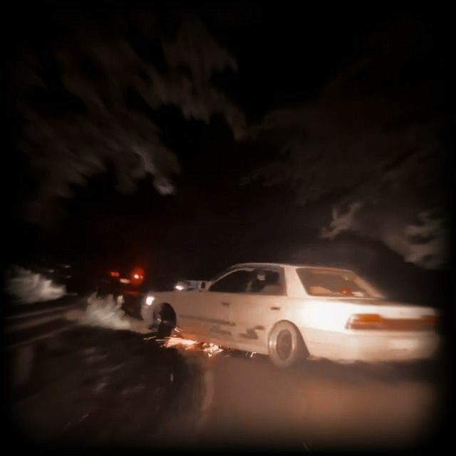 a white car driving down a street at night