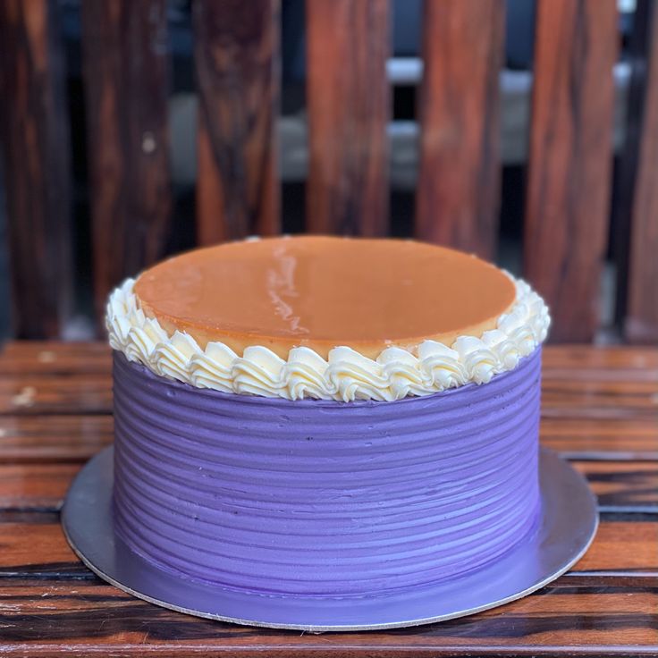 a purple cake with white frosting sitting on top of a wooden table