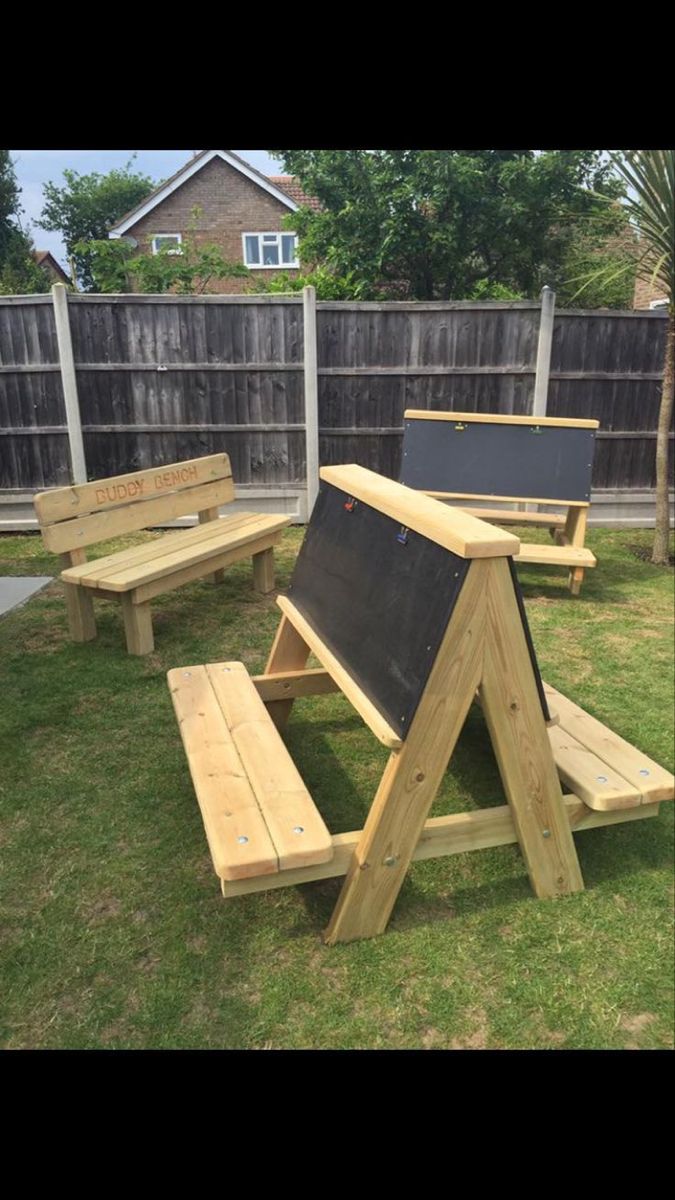 an outdoor picnic area with benches and chalkboard